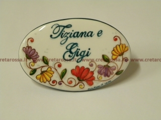 cod.art: nc99 - Mattonella in ceramica ovale 8,5x13 circa con decoro "Fiori di cera" e scritta personalizzata. 